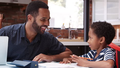 Father-Helps-Son-With-Homework-In-Kitchen-At-Home