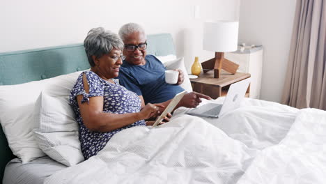 Senior-Couple-Lying-In-Bed-Using-Digital-Devices
