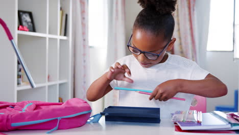 Young-Girl-Wearing-Glasses-Packing-Bag-For-School-In-Bedroom