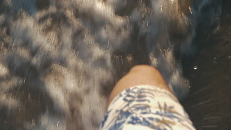 Barefoot-man-walking-in-sea-waves-washing-shore-Summer-vacation-on-coast