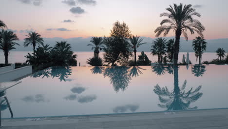 Escena-Del-Atardecer-Del-Resort-Con-Piscina-Con-Vista-Al-Mar-Y-Palmeras-Turquía