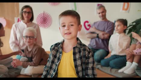 Portrait-of-a-little-boy-in-a-checkered-shirt-and-a-yellow-T-shirt-who-looks-at-the-camera-against-the-background-of-a-club-preparing-children-for-school.-The-little-boy-at-his-first-lesson-in-the-school-preparation-club