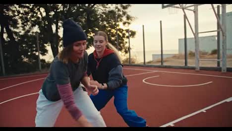 Un-Trío-De-Chicas-Rubias-Juegan-Al-Baloncesto-Con-Una-Pelota-De-Baloncesto-Naranja-En-La-Cancha-De-Baloncesto-Roja-Y-Una-De-Ellas-Lanza-La-Pelota-Al-Aro-De-Baloncesto-Durante-Su-Entrenamiento-Matutino.