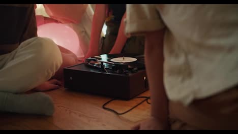 A-group-of-preschool-children-sit-in-a-circle-and-look-at-the-record-player-and-listen-to-music.-Interested-children-look-at-a-record-player-in-a-club-preparing-children-for-school