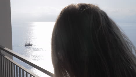 Emotional-woman-having-mobile-phone-talk-on-the-balcony-with-sea-view