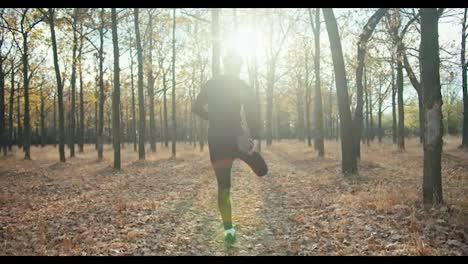 Rückansicht-Eines-Mannes-Mit-Lockigem-Haar-In-Einer-Schwarzen-Sportuniform,-Der-Sich-Vor-Dem-Start-Seines-Rennens-Am-Morgen-Im-Herbstwald-Aufwärmt.-Gesunde-Gewohnheiten-Und-Gesunder-Lebensstil:-Joggen-Am-Morgen