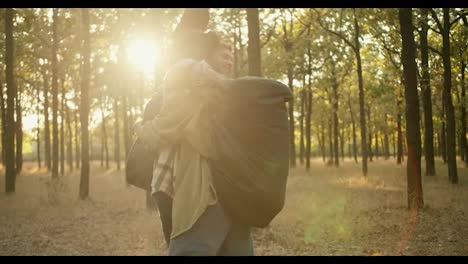 2-Glückliche-Freunde-Trafen-Sich-Beim-Wandern.-Ein-Brünetter-Mann-In-Einer-Hellgrünen-Jacke-Mit-Einem-Großen-Wanderrucksack-Und-Ein-Blonder-Mann-Mit-Hut-Und-Kariertem-Hemd-Kommen-Aufeinander-Zu,-Umarmen-Sich-Vor-Der-Kulisse-Eines-Sommerwaldes-Und-Setzen-Ihre-Wanderung-Fort.