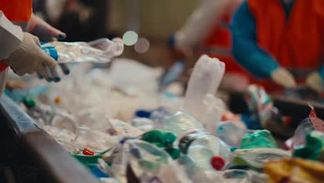 Close-up-shot-of-the-hands-of-workers-who-sort-plastic-bottles-and-garbage-near-a-conveyor-belt-at-a-waste-and-plastic-recycling-plant