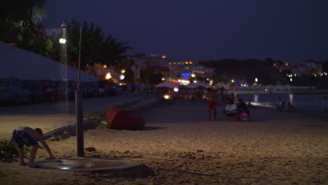 Playa-Con-Gente-En-La-Ciudad-Turística-De-Noche-Grecia