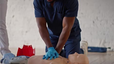 Close-up-shot-from-below:-A-professional-Black-male-doctor-conducts-practice-sessions-on-medical-care,-doing-artificial-respiration-on-a-mannequin-for-the-public