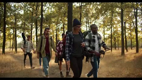 Happy-people-in-hiking-clothes-and-with-backpacks-walk-in-pairs,-one-after-another,-through-the-summer-forest.-Happy-group-of-people-While-hiking-in-summer