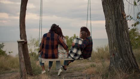 Dos-Parejas-De-Enamorados-Se-Balancean-En-Un-Columpio-De-Madera-Y-Se-Abrazan.-Descansan-En-La-Casa-De-Campo-Junto-Al-Mar.