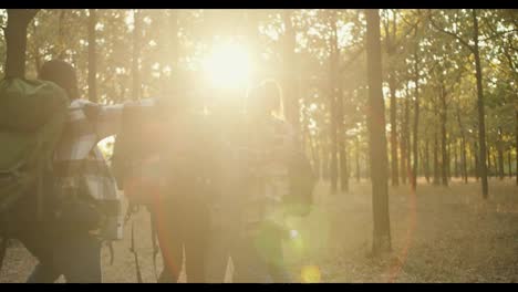 A-group-of-happy-friends-on-a-hike-run-up-to-each-other-and-hug,-people-in-hiking-clothes-with-backpacks.-Happy-team-on-a-hike-in-a-sunny-summer-forest