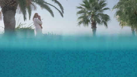 Mom-with-baby-having-outdoor-walk-near-swimming-pool