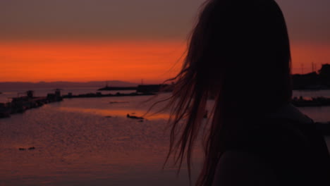 Lonely-woman-staring-at-small-harbour-in-the-evening