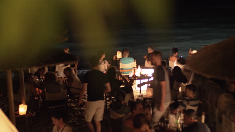 Gente-Relajándose-En-La-Cafetería-De-La-Playa-Por-La-Noche