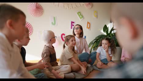 Una-Chica-Rubia-Con-Un-Peinado-Bob,-Gafas-Y-Una-Camisa-Blanca,-Se-Comunica-Con-Un-Niño-Albino-Con-Gafas-Durante-Una-Lección-En-Un-Club-De-Preparación-De-Niños-Para-La-Escuela.