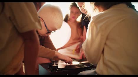 Ein-Albino-Junge-Mit-Weißem-Haar-Und-Runder-Brille-Untersucht-Und-Berührt-Mit-Seinen-Freunden-In-Einem-Club-Zur-Schulvorbereitung-Einen-Plattenspieler