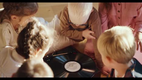 Los-Niños-En-Edad-Preescolar-Se-Sientan-Alrededor-De-Un-Tocadiscos-Especial-Escuchando-Música-Y-Comunicándose-Entre-Ellos-En-Una-Habitación-Soleada-Y-Acogedora-En-Un-Club-Para-Preparar-A-Los-Niños-Para-La-Escuela.