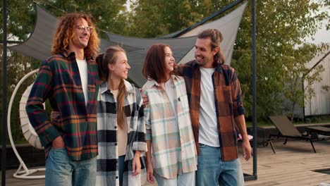 Two-boys-and-two-girls-in-checkered-shirts-are-walking-and-hugging.-Two-guys-high-five-each-other.-Rest-in-the-country-house