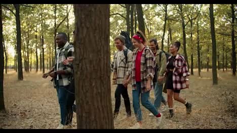 A-happy-group-of-people-in-plaid-shirts-and-hiking-clothes-go-on-their-small-hike-through-the-summer-forest.-Multi-national-group-on-a-hike