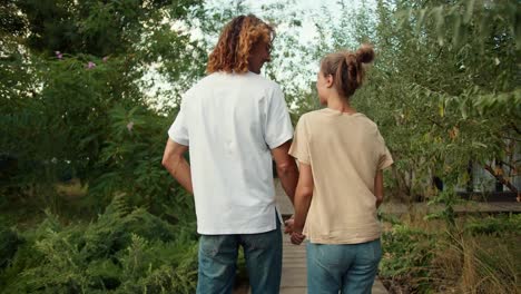 Shooting-from-behind:-A-girl-with-her-curly-boyfriend-in-a-white-T-shirt-are-walking-in-the-country-house