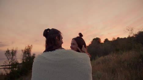 Disparo-Desde-Atrás:-Una-Pareja-De-Enamorados,-Cubiertos-Con-Una-Manta,-Se-Abrazan-Y-Miran-La-Puesta-De-Sol.-Descanso-Tranquilo-Fuera-De-La-Ciudad.-Descanso-En-La-Casa-De-Campo.