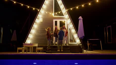 A-company-of-two-boys-and-two-girls-dance-together-against-the-background-of-glowing-lights.-Resting-at-a-party-outside-the-city.-Rest-in-the-country-house