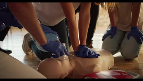 Close-up-shooting:-Two-people-perform-CPR-using-a-mannequin-and-an-Ambu-resuscitation-bag.-The-girl-presses-on-the-mannequin's-chest.-Practical-training.-Training-in-first-aid