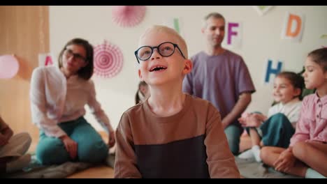 happy-Cheerful-albino-boy-in-round-glasses-laughs-and-smiles-against-of-his-first-lesson-in-preparation-for-school.-Portrait-of-an-albino-boy-at-his-first-lesson-at-school