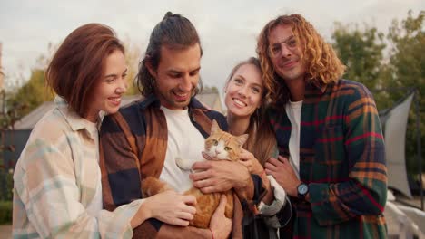 Portrait:-two-girls-and-two-boys-in-checkered-shirts-hug-and-stroke-a-red-cat.-Rest-in-the-country-house