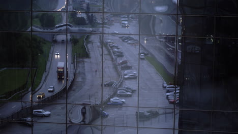 Reflex-of-street-with-car-traffic-in-glassy-building-facade