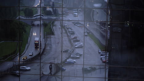 Reflejo-De-La-Calle-Con-Tráfico-De-Automóviles-En-La-Fachada-Del-Edificio-Vidrioso.