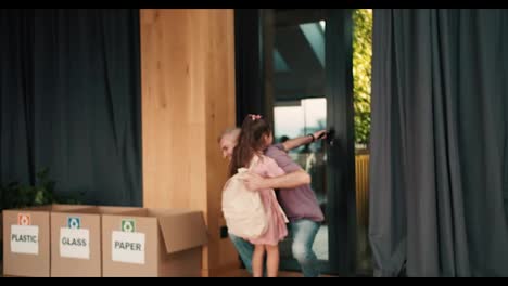 A-Happy-little-brunette-girl-in-a-pink-skirt-with-a-white-backpack-runs-to-her-dad-after-lessons-in-a-club-for-preparing-children-for-school