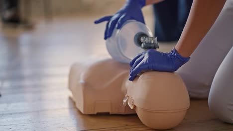 Close-up-shooting-from-the-bottom:-a-professional-female-doctor-conducts-practical-training-in-medical-care,-doing-artificial-respiration-on-a-mannequin-using-an-Ambu-resuscitation-bag-for-the-public