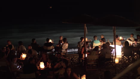 Gente-Disfrutando-De-La-Noche-En-El-Café-De-La-Playa-En-La-Orilla.