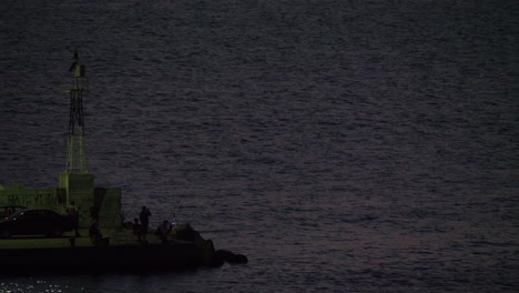 Hombres-Pescando-Desde-El-Muelle-Con-La-Luz-Del-Mar-Parpadeando-En-Grecia