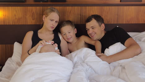 Happy-parents-with-children-lying-in-bed-together