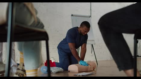 Bottom-view:-A-Black-male-doctor-in-blue-uniform-conducts-a-practice-session-showing-artificial-respiration-on-a-medical-mannequin