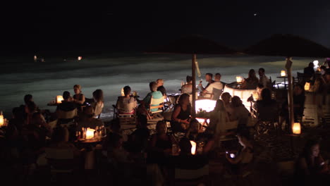 Gente-Relajándose-En-Una-Cafetería-Al-Aire-Libre-A-Orillas-Del-Mar-Por-La-Noche