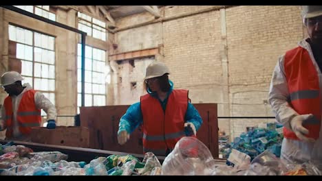 Un-Trío-De-Trabajadores-En-Una-Planta-De-Reciclaje-De-Residuos.-Personas-En-Uniforme-Clasifican-Las-Botellas-De-Plástico-Según-El-Color-Durante-El-Reciclaje-En-La-Planta.