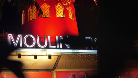 Moulin-Rouge-Bei-Nacht,-Blick-Durch-Die-Baumblätter