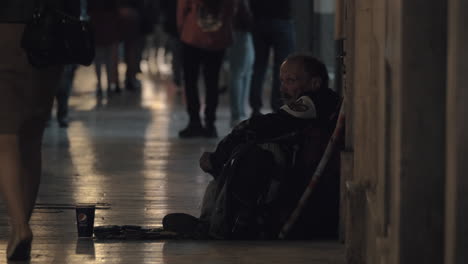 Hombre-Mendigo-Sentado-En-Una-Calle-Muy-Transitada