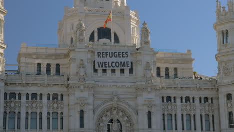 Cybele-Palast-Mit-Willkommensbanner-Für-Flüchtlinge-Und-Plaza-De-Cibeles-In-Madrid,-Spanien