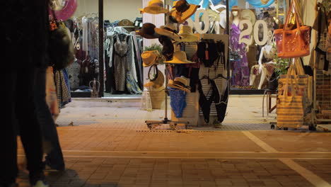 Calle-Nocturna-Con-Gente-Pasando-Por-Una-Tienda-De-Ropa.