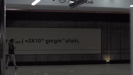 Man-waiting-for-subway-train-at-the-station-with-global-warming-equation-Paris