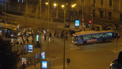 Vista-Nocturna-De-La-Ciudad-Con-Gente-Cruzando-La-Calle-Y-Tráfico-De-Transporte-En-Madrid.