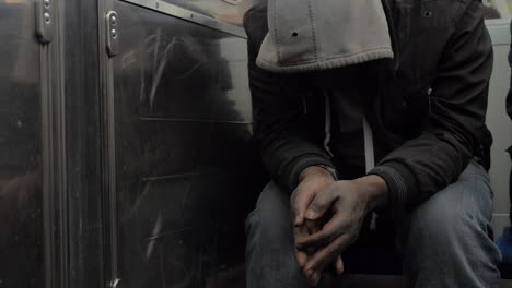 Obdachloser-In-Der-U-Bahn-Versteckt-Sein-Gesicht-Unter-Der-Haube