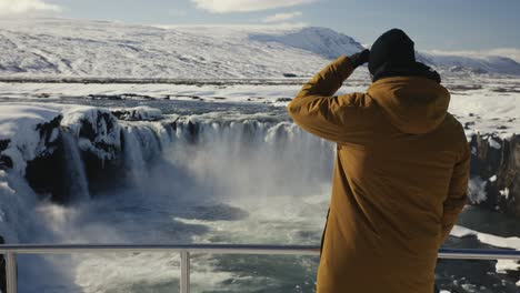 Tourist-come-near-metal-safety-barrier-and-look-at-Godafoss-waterfall-landscape