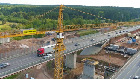 Kauno-Kranai-logo-on-industrial-crane-in-A1-bridge-construction-site,-aerial-orbit-view